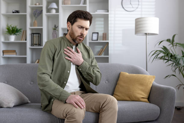 istock Man experiencing chest pain sitting on sofa at home 2167834760