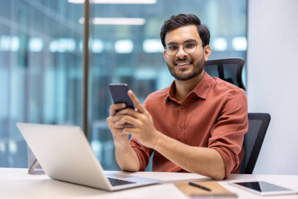 istock Confident businessman in modern office using smartphone and laptop 2167835034