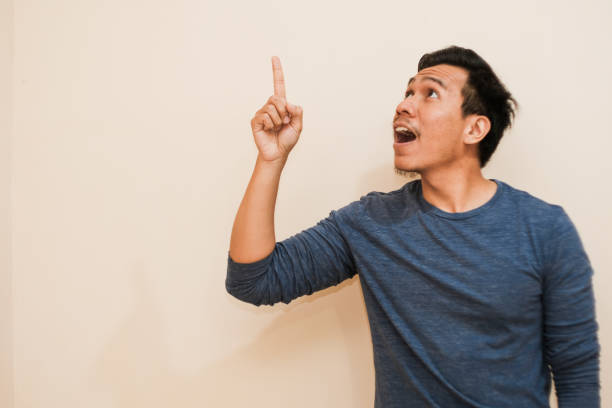 istock Southeast Asian man smiling to the camera while pointing his up 2167836190