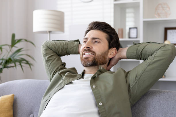 istock Relaxed man sitting on sofa with hands behind head at home, enjoying leisure time 2167836593