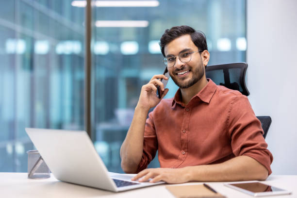 istock Smiling businessman talking on phone while working at desk in office 2167837250