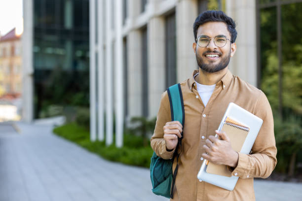 istock Confident student holding books and backpack outside modern university building 2167837569