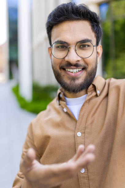 istock Smiling man in glasses having outdoor conversation on video call 2167838514