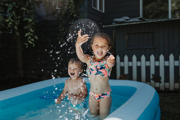 istock Adorable girl splashes water in backyard pool 2167839900