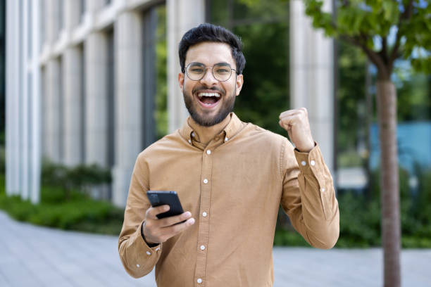 istock Happy man celebrating success outside modern office building 2167840132