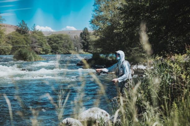 istock Fisherman casts his line in the water while standing riverside 2167840745