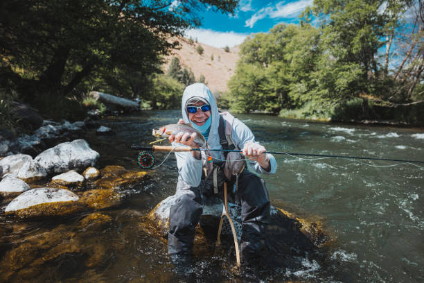 istock Man smiles while holding up fish he caught 2167840746