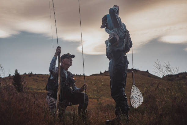 istock Fisherman kneels on the ground while chatting with his friend 2167840762