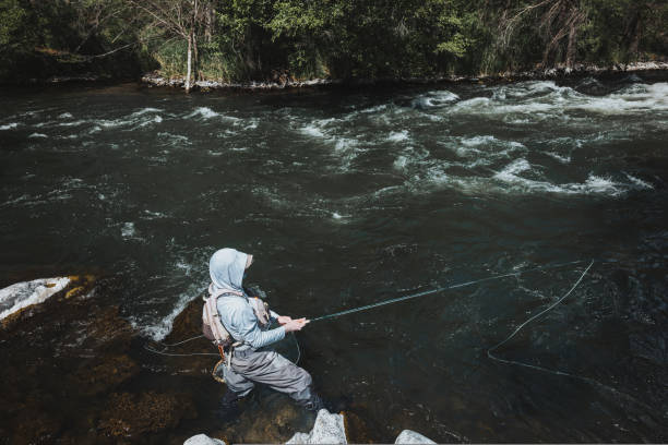 istock Fisherman holds a rod while fly fishing in the river 2167840791