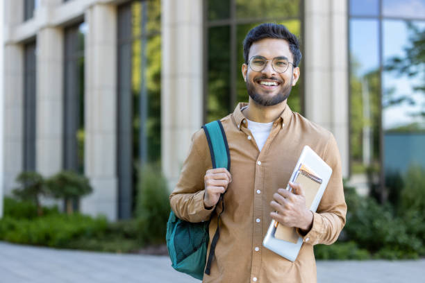 istock Smiling hispanic student standing outside academic building with backpack and notebooks 2167840903