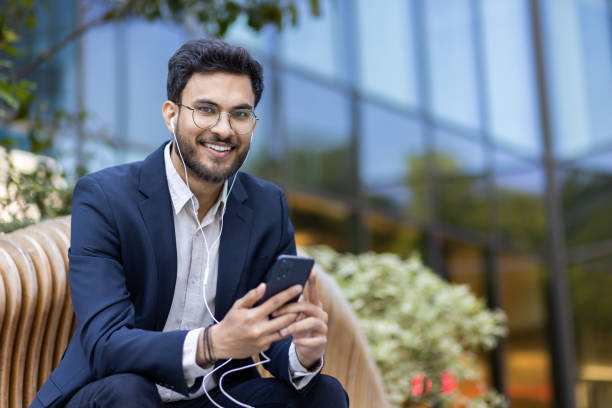 istock Young professional enjoying music on smartphone while sitting outdoors in business district 2167840929