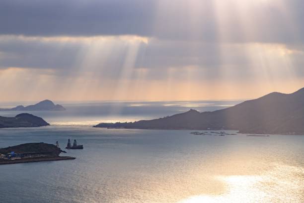 Sunbeams Through Clouds Over Serene Coastal Waters and Distant Islands