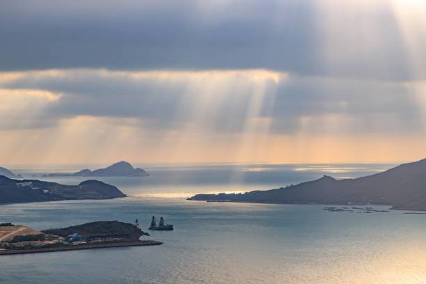 istock Sunbeams Through Clouds Over Serene Coastal Waters and Distant Islands 2167844654
