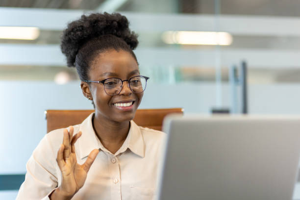 istock Smiling woman waving during video call in modern office setting 2167845288