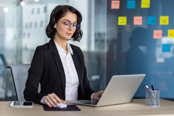 istock Confident businesswoman working on laptop in modern office setting 2167845314