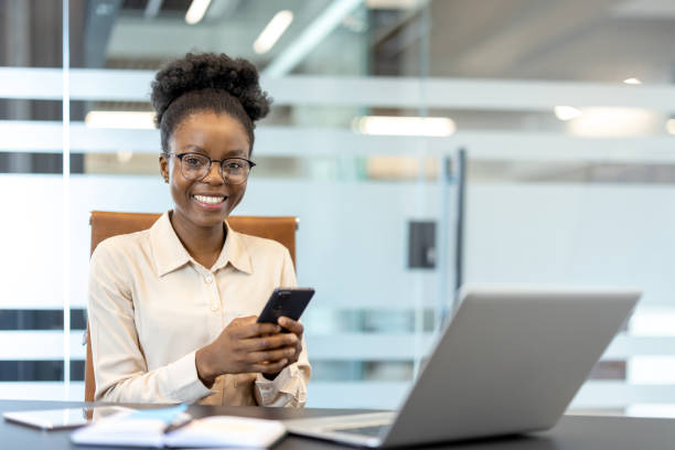 istock Young African American businesswoman smiling at workplace while using phone in office 2167845596