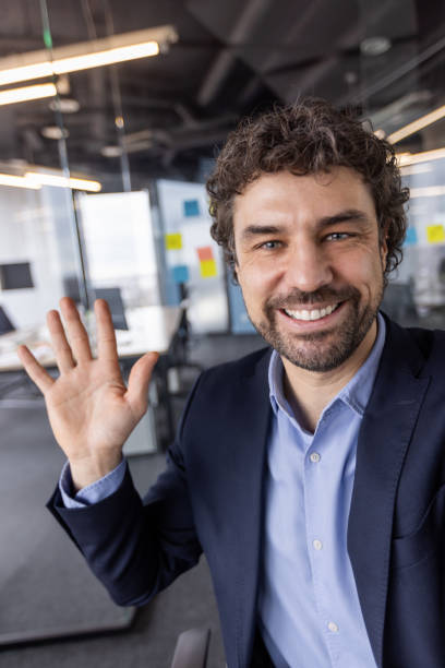 istock Smiling businessman waving hand during video call in modern office 2167845618