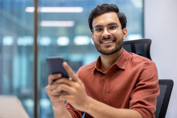 istock Smiling business professional using smartphone at modern office desk 2167846998