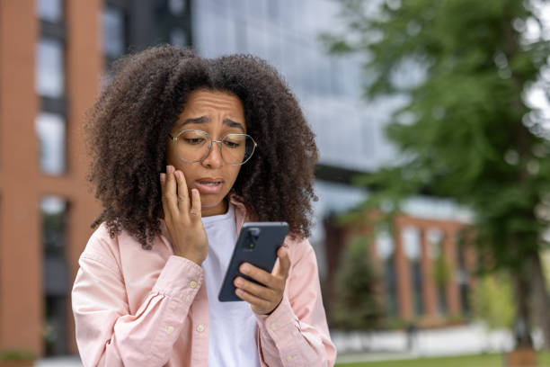 istock Young female student looking worried while reading message on phone near university campus 2167848194