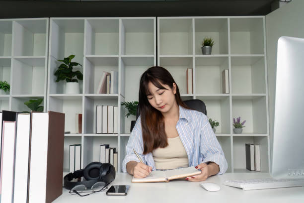istock Young Student Studying Online at Home Desk with Books and Computer in Modern Minimalist Workspace 2167848662