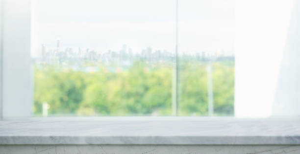 istock Selective focus.A clean bright marble countertop in the foreground, with blurred view of a green park landscape and city skyline background. Ideas for design mockups 2167848883