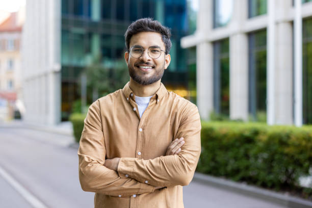 istock Smiling young man with glasses standing outside modern office building 2167848989