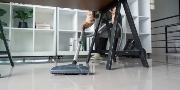 istock Maid Skillfully Vacuuming Under Desk in Modern Office Environment 2167850617
