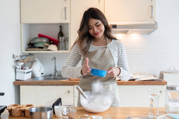 istock Smiling Woman Adding Ingredients for Baking in Home Kitchen 2167850674