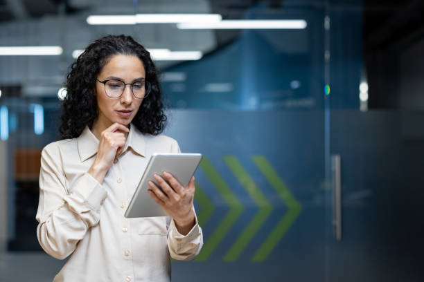 Businesswoman with tablet in modern office space makes important decisions