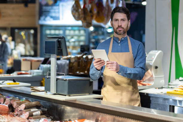 istock Male butcher using digital tablet behind counter at deli shop 2167852426