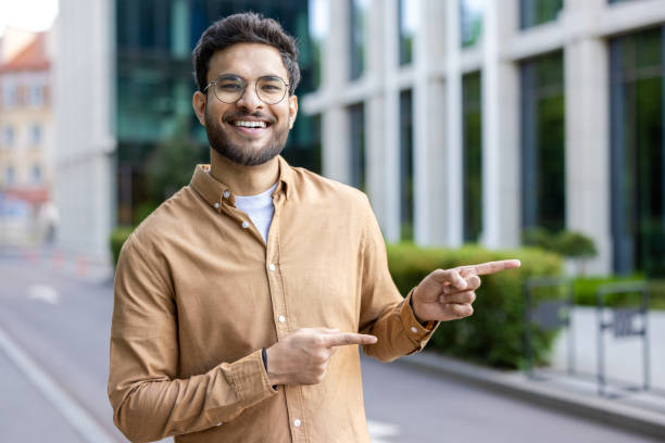 istock Happy man outdoors in city pointing with both hands, smiling confidently 2167853884