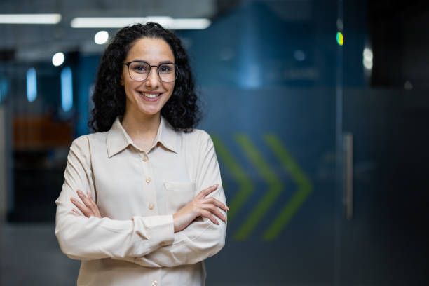 istock Confident young woman with glasses smiling in modern office setting 2167854181