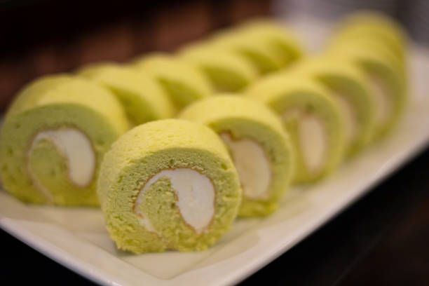 Delicious Matcha Swiss Roll Cake with icing cream on white plate
