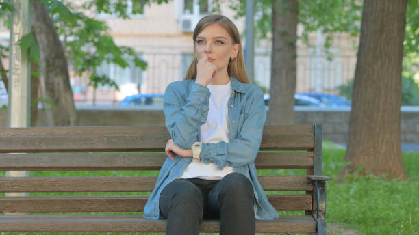 istock Woman Thinking while Sitting on Bench in Park 2167858962