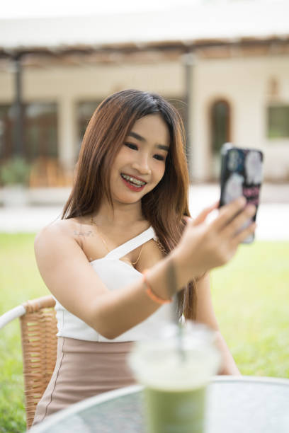 istock A woman is taking a selfie with her cell phone while sitting at a table with a c 2167859849