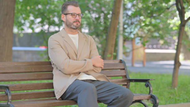 istock Middle Aged Man Brainstorming while Sitting Outdoor on Bench 2167859914