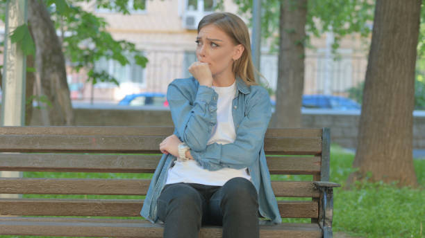 istock Depressed Young Woman Feeling Tense while Sitting on Bench in Park 2167860485