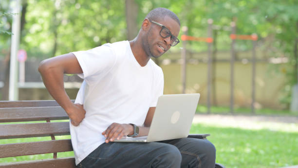 istock Young African Man with Back Pain Using Laptop Outdoor 2167861264
