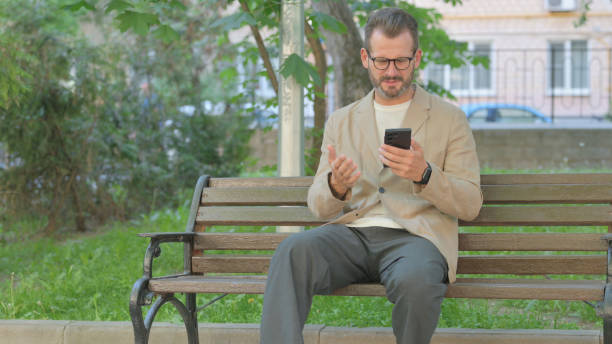 istock Young Man Upset by Loss on Phone while Sitting Outdoor 2167861583