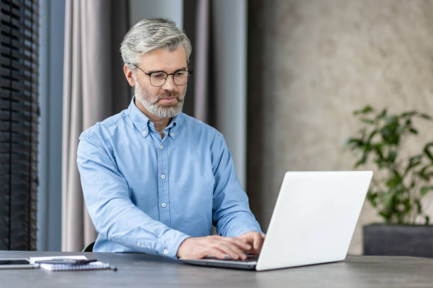 istock Mature businessman working on laptop in modern office environment 2167861988
