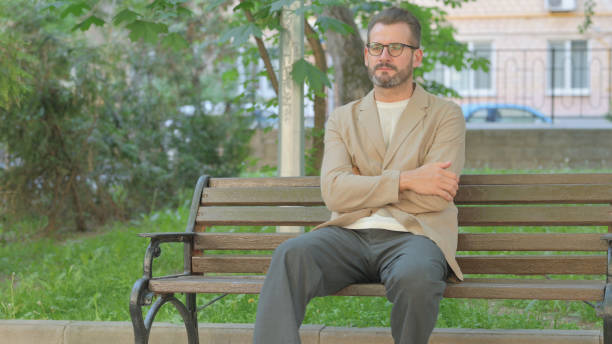 istock Pensive Young Man Sitting Outdoor on Bench 2167862894