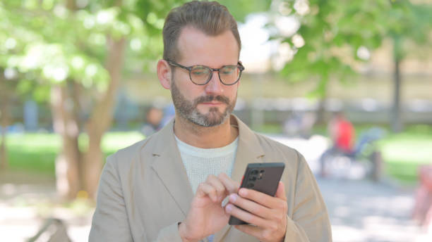 istock Businessman Using Phone Outdoor in Park 2167863041