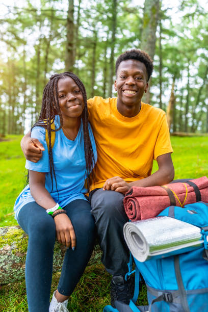 African friends sitting on fallen tree and resting during hiking