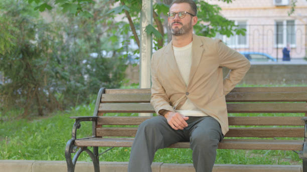 istock Young Man with Spinal Pain Sitting Outdoor on Bench 2167863905