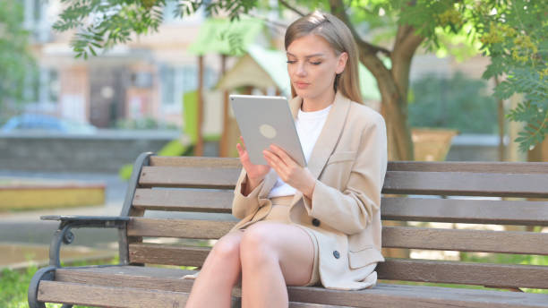 istock Businesswoman Using Digital Tablet while Sitting Outdoor on Bench 2167864072