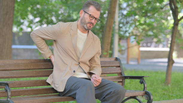 istock Middle Aged Man with Back Pain Sitting Outdoor on Bench 2167865732