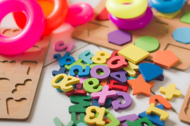 A vibrant collection of educational toys, including alphabet puzzles and stacking rings, are scattered on a clean white floor. Educational toys backgrounds for kids