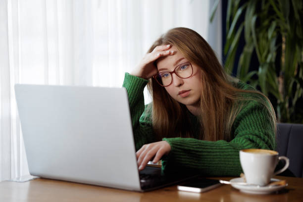 istock tired girl working online with laptop and drinking coffee, online learning 2167871484