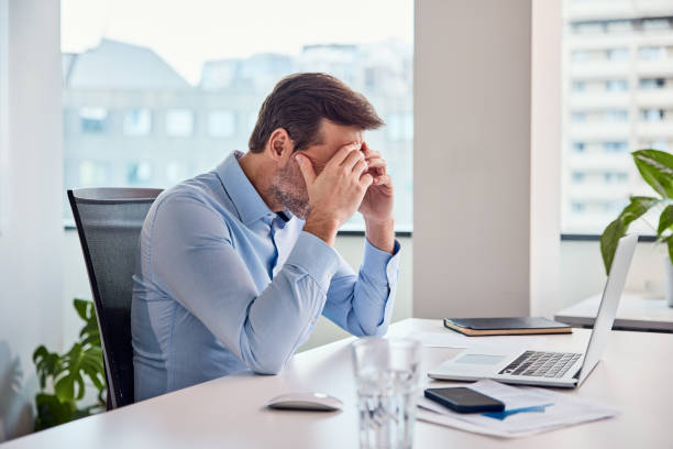 istock Stressed businessman sitting at a desk with head in hands, feeling overwhelmed. 2167876263