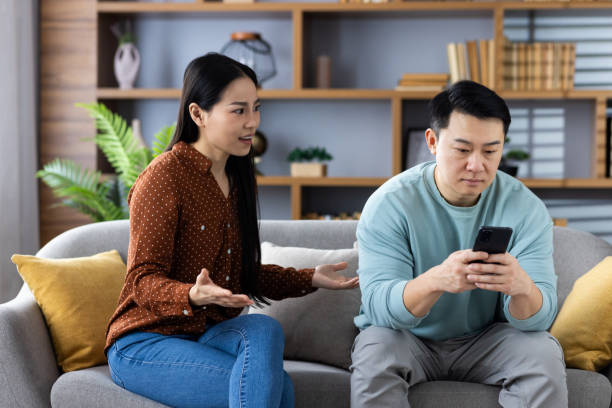 istock Asian couple arguing on couch, man distracted by phone 2167876771